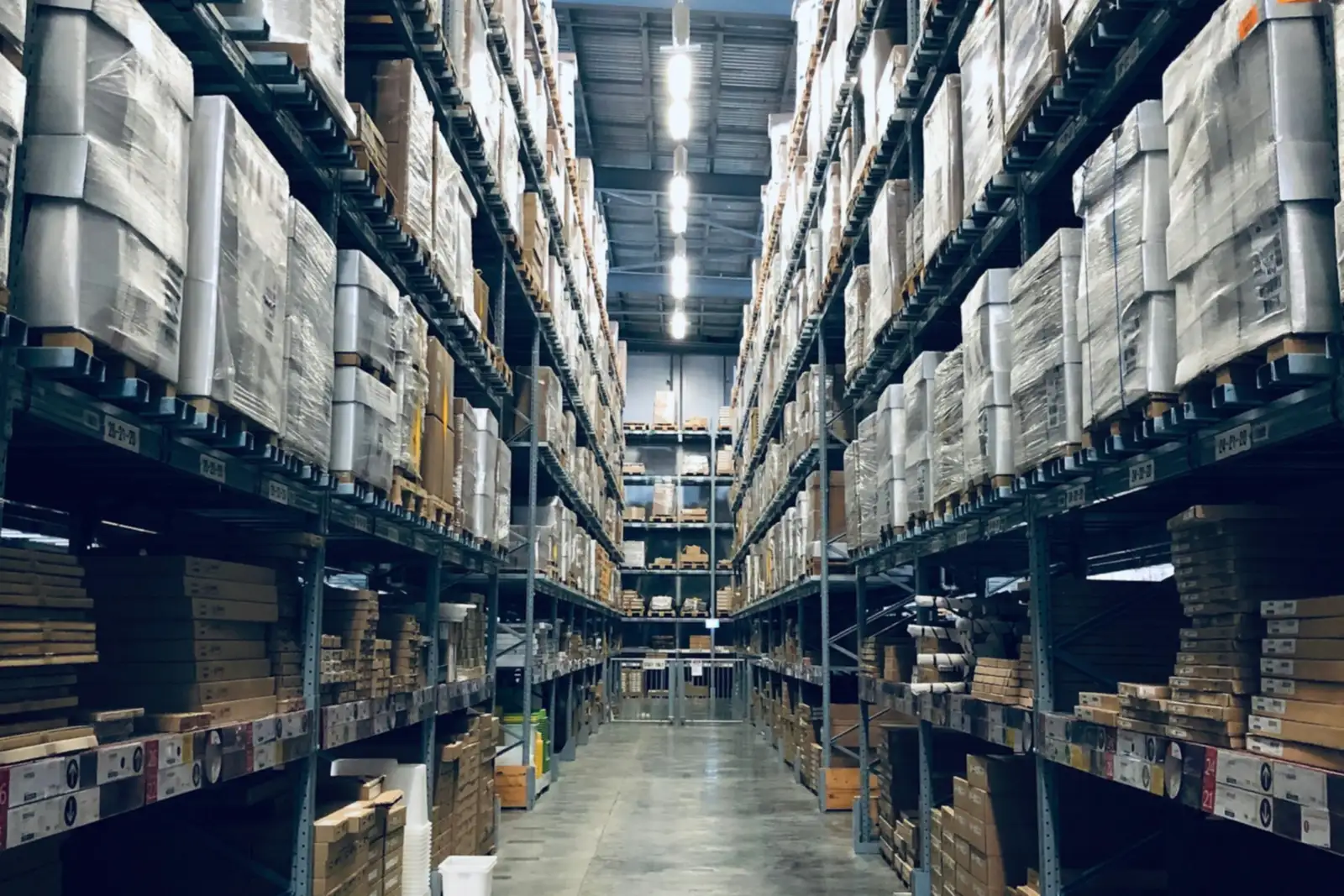Long warehouse aisle lined with tall pallet racks of boxed goods