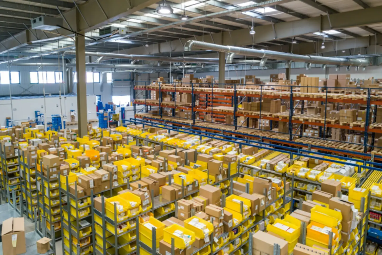 Large warehouse interior with rows of shelving, yellow bins and cardboard boxes
